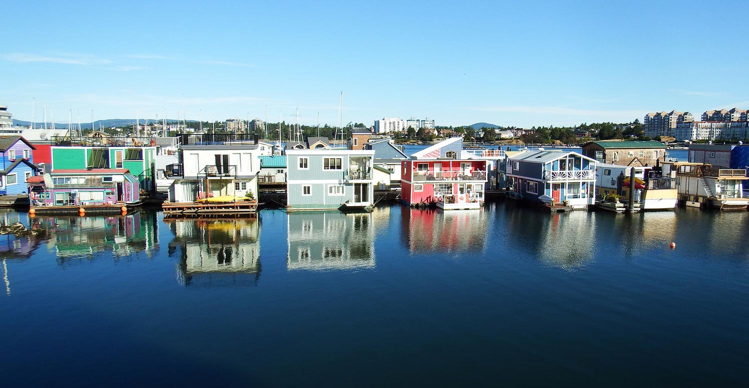 House boats rest on calm harbour waters at Fisherman's Wharf in Victoria, BC.